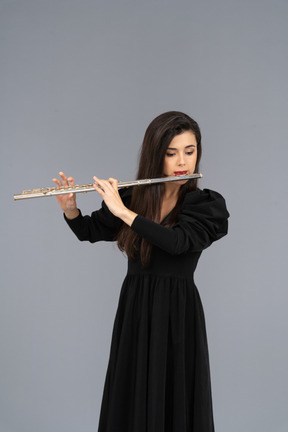 Front view of a serious young lady in black dress playing the flute