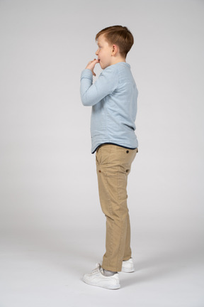 Cute boy standing in profile and whistling
