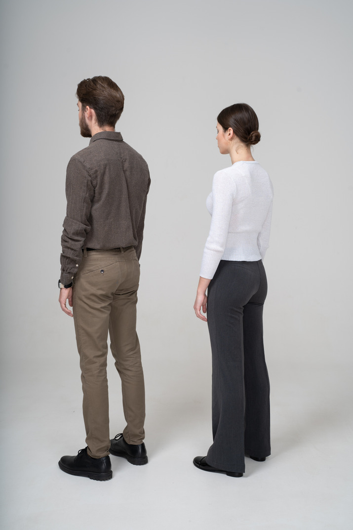 Three-quarter back view of an unrecognizable young couple in office clothing standing still