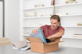 A man opening a box with a pair of jeans in it