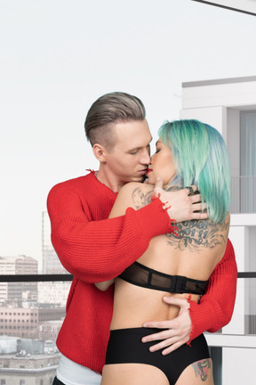 A man is kissing a woman in an underwear on a balcony