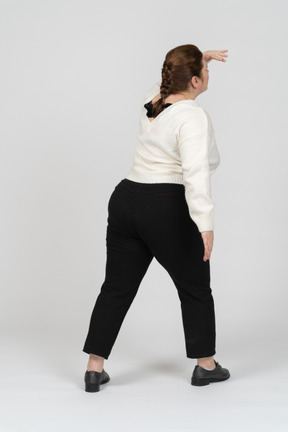 Rear view of plump woman in casual clothes looking for someone