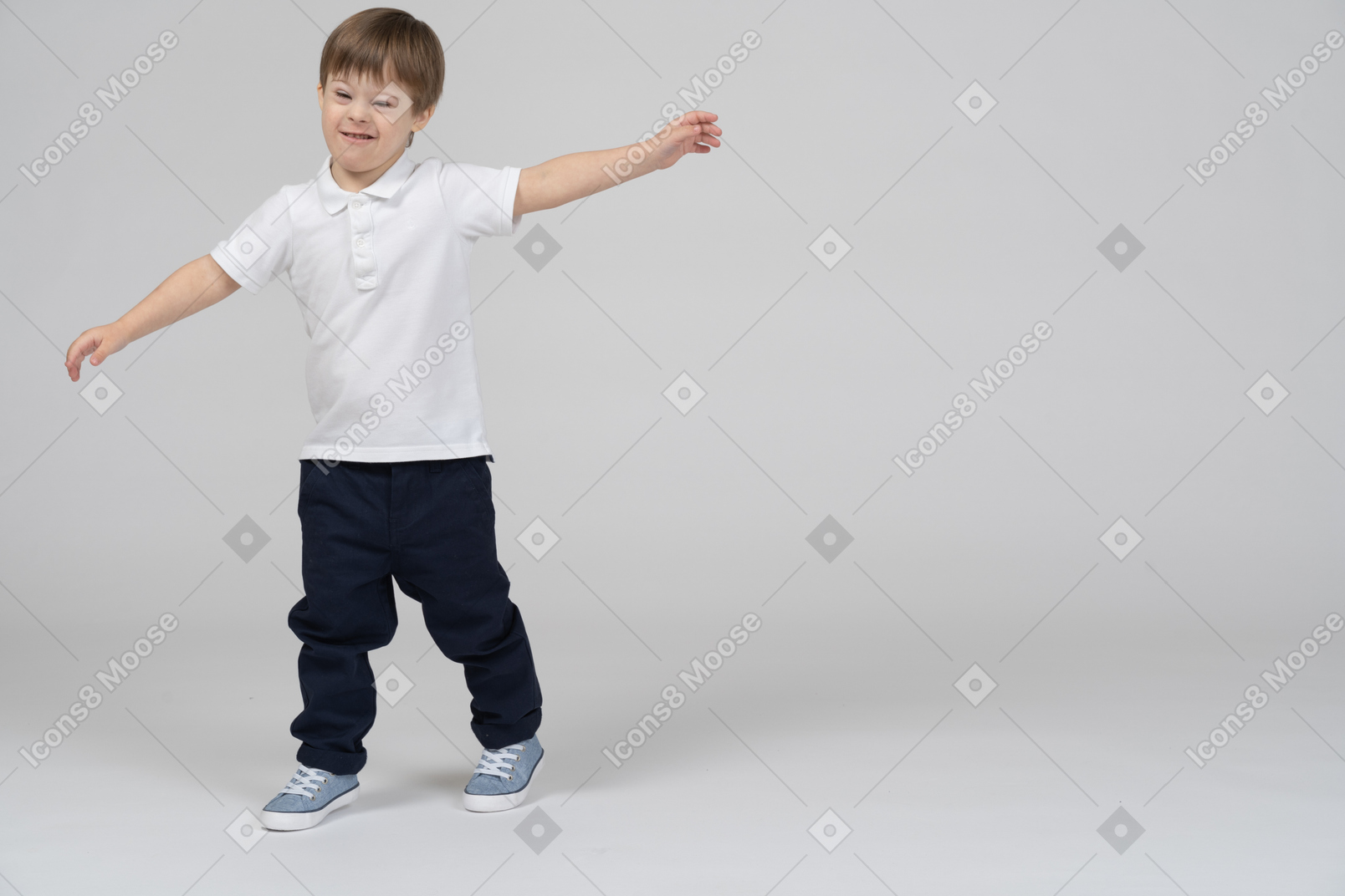 Вид спереди на мальчика, гримасничающего с раскинутыми в стороны руками