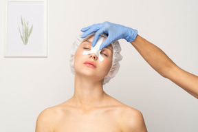 Nurse applying bandage to young woman's nose