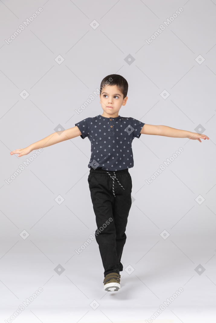 Front view of a cute boy balancing on one leg and outstretching arms