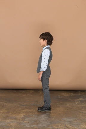 Side view of a cute boy in grey suit