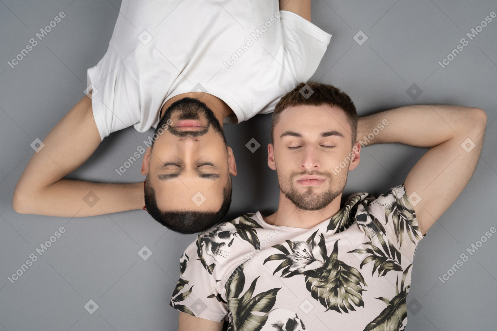 Flat lay of two young caucasian men lying symmetricly head to head with eyes closed