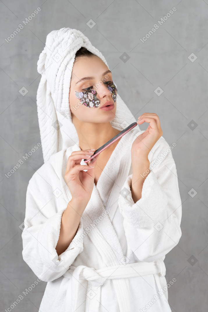 Woman in bathrobe filing her nails