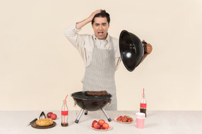 Gasping young caucasian man preparing a bbq