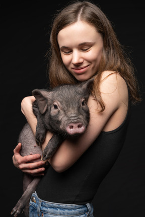 Hermosa chica con cerdo en miniatura