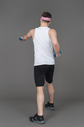 Man exercising with dumbbells back to camera