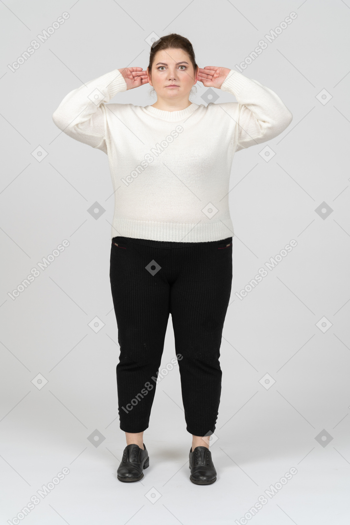 Plump woman in casual clothes touching ears and looking at camera