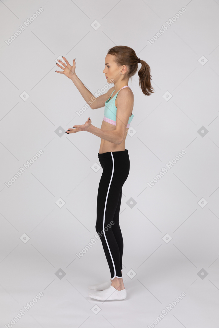 Side view of a teen girl in sportswear raising hands and arguing
