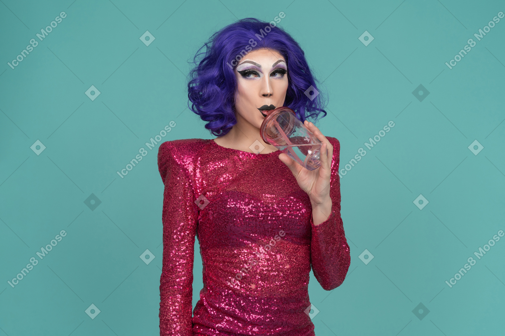 Drag queen con vestido rosa de lentejuelas mirando de lado mientras toma una copa