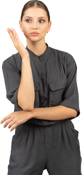 Front view of a young woman in a jumpsuit holding a cotton pad