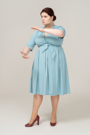 Вид спереди женщины в синем платье, показывающей размер чего-то