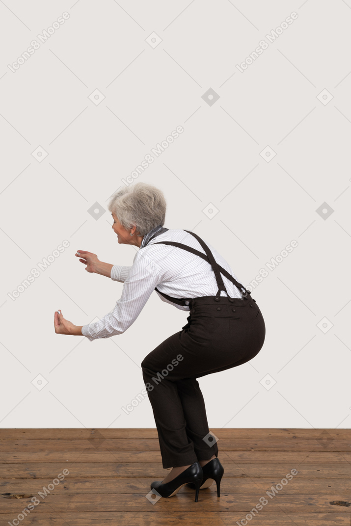 Vista lateral de una anciana gesticulante en cuclillas