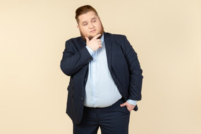 Pensive young overweight man touching chin