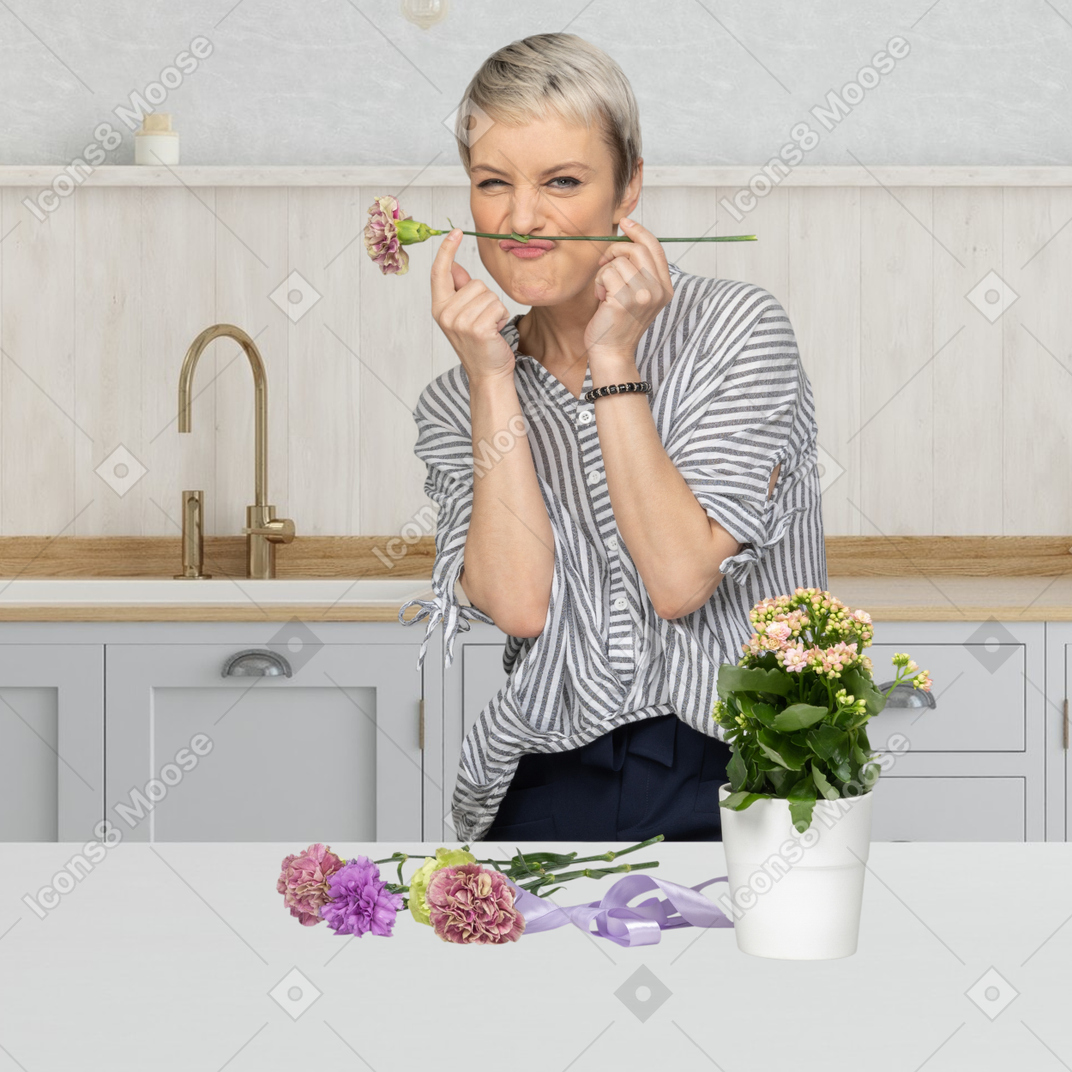 Young woman watering flowers in the kitchen