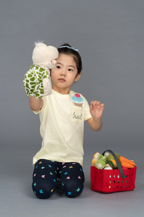 Portrait of a little girl feeding a tortoise puppet