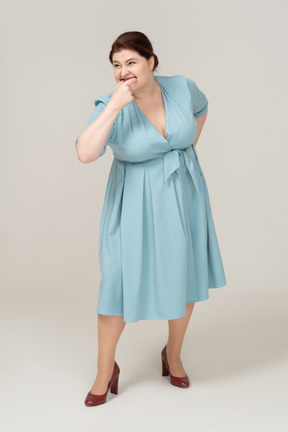 Vista frontal de uma mulher de vestido azul assobiando
