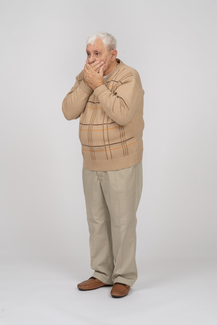 Вид спереди испуганного старика в повседневной одежде, закрывающего рот руками