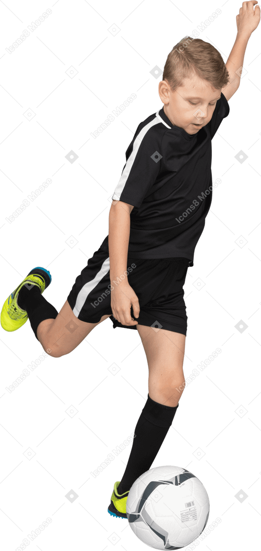 Vista di tre quarti di un ragazzino in uniforme di calcio che calcia un pallone