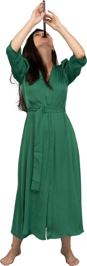 Vue de face d'une jeune femme en robe verte jouant de la flûte en se penchant en arrière