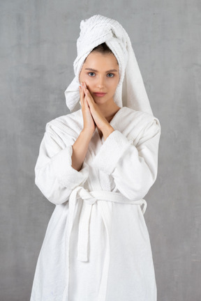 Femme en peignoir posant avec les mains jointes