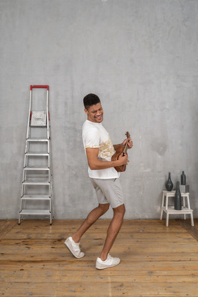 Three-quarter back view of a man rocking out on ukulele and leaning back slightly
