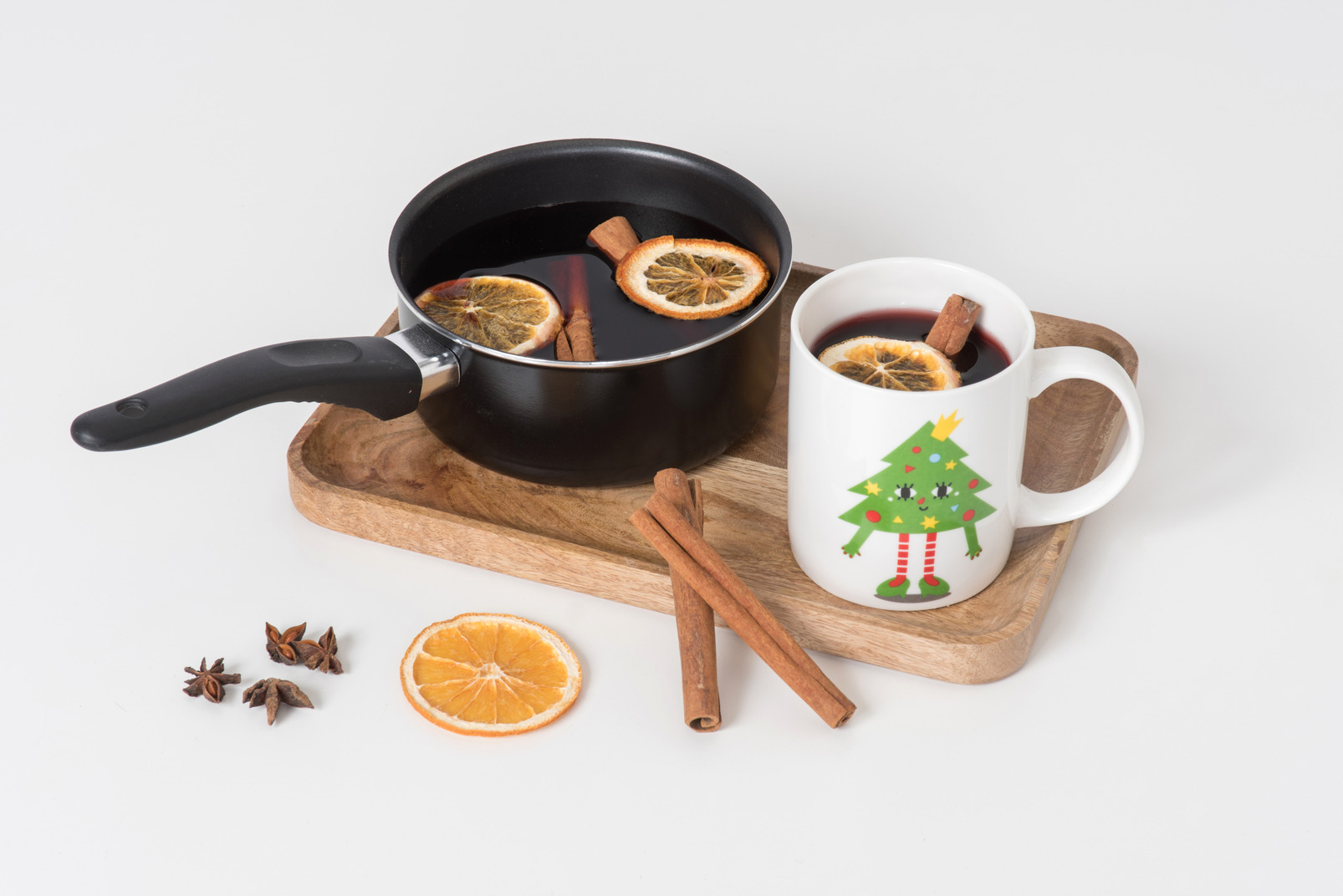 Mulled wine in pan and cup standing on white board