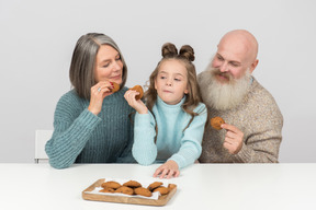 Бабушка и дедушка и внучка едят печенье