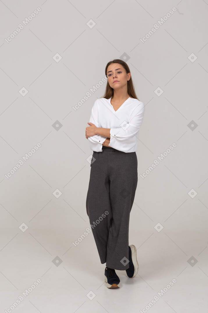 Front view of a bossy young lady in office clothing walking with her arms crossed