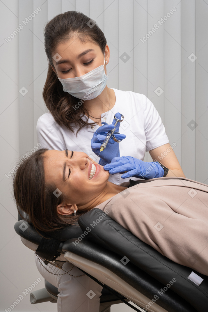 Nervous woman getting anesthetic injected by dentist