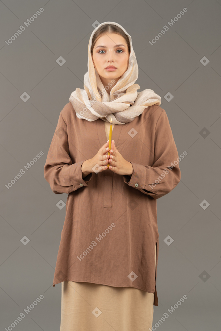 Religious woman holding a candle with both hands