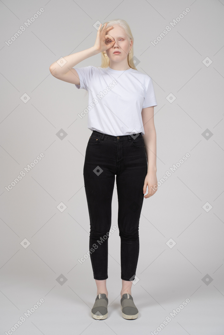 Young woman making okay sign over her eye
