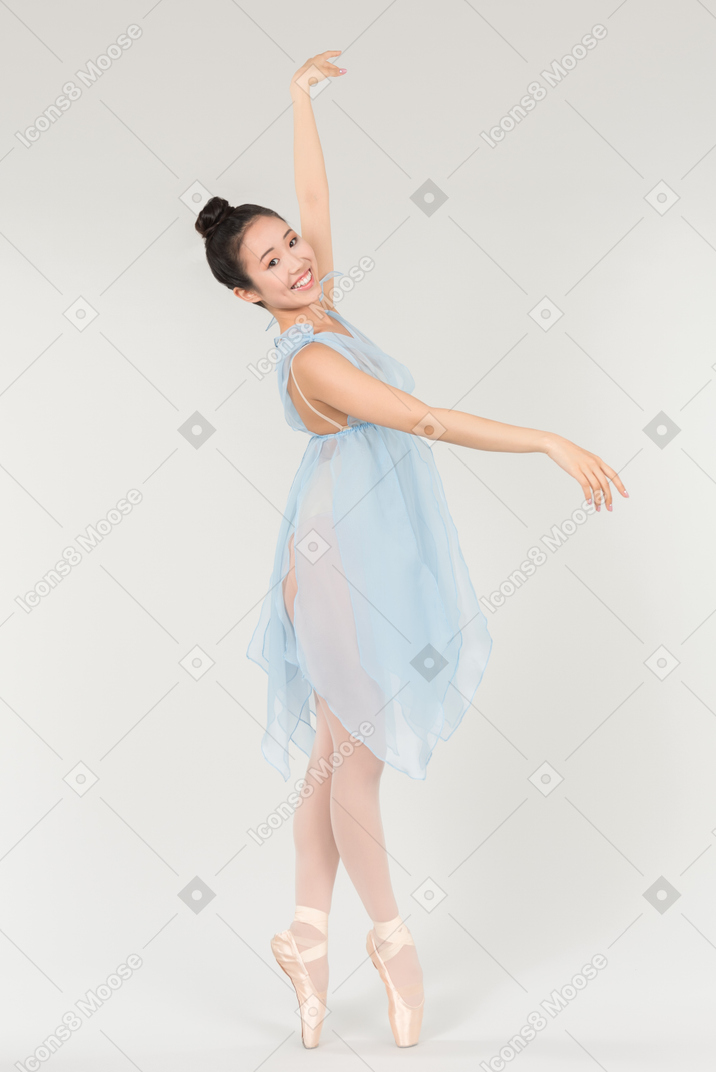 Young asian ballerina in a transparent light blue dress standing in a classical ballet pose