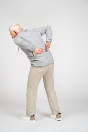 Back view of man standing with his hands on his lower back