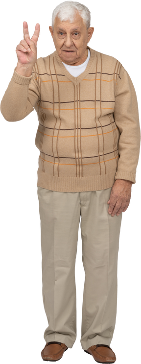 Vista frontal de un anciano con ropa informal que muestra el signo v