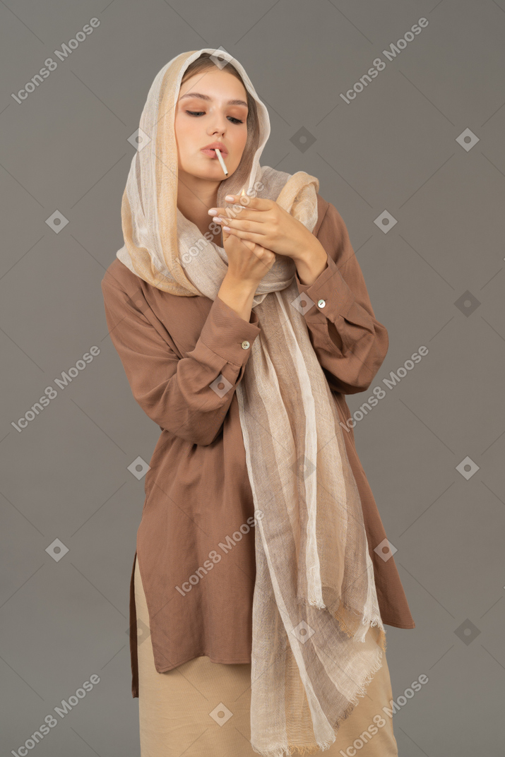 Young woman in headscarf lighting cigarette