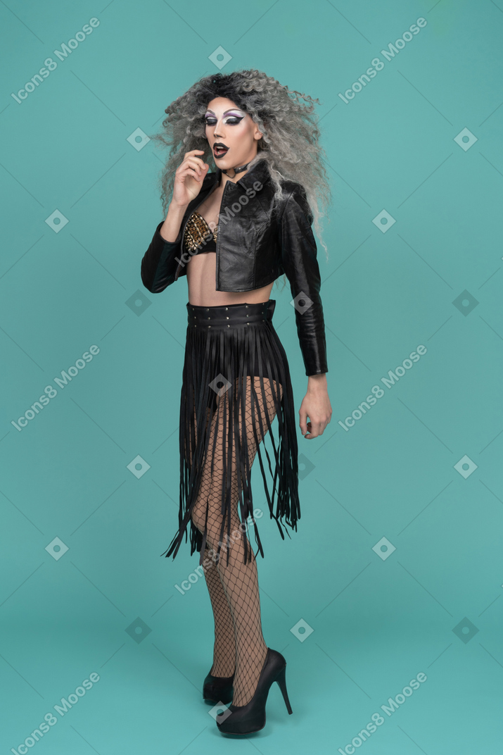 Drag queen in leather jacket with finger next to mouth
