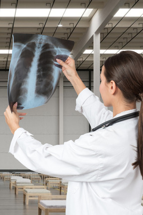 Standing back to camera female doctor looking at x-ray scan she's holding