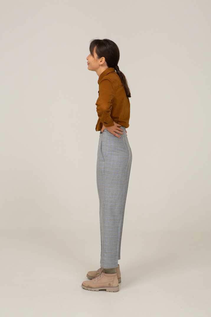 Side view of a young asian female in breeches and blouse putting hands on hips