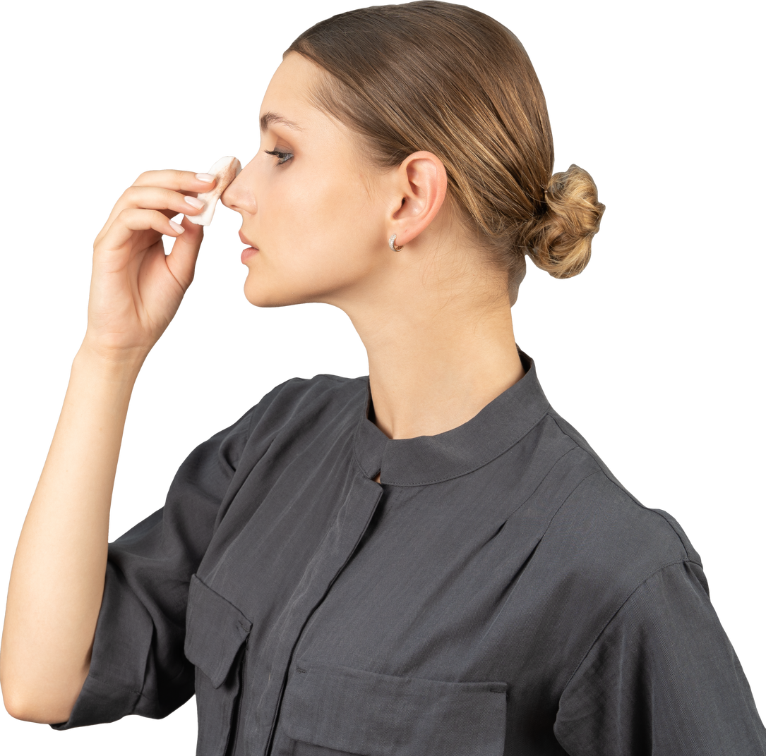 Side view of a young woman in a jumpsuit removing concealer