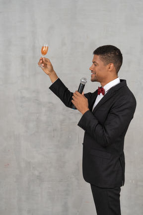 Hombre con ropa formal levantando una copa y proponiendo un brindis