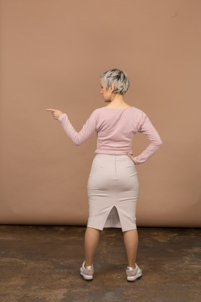Rear view of a woman in casual clothes pointing with finger