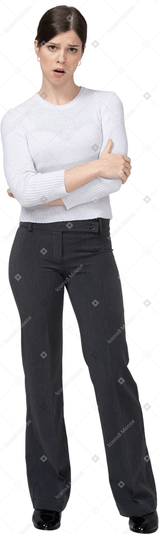Front view of a displeased young woman in office clothing crossing hands