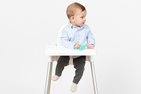 Baby boy sitting in highchair and holding toy