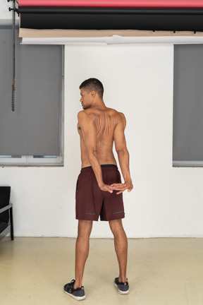 Back view of young man doing reverse shoulder stretch