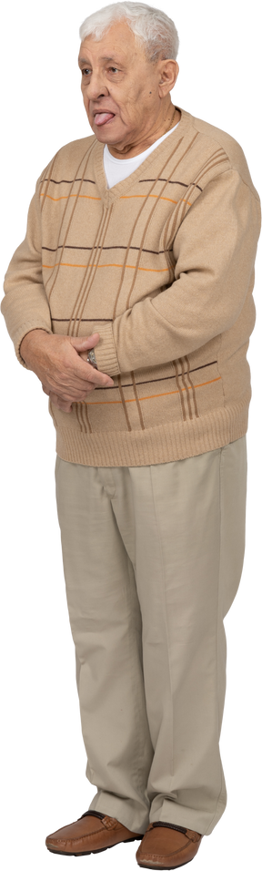 Vista frontal de um velho em roupas casuais, mostrando a língua